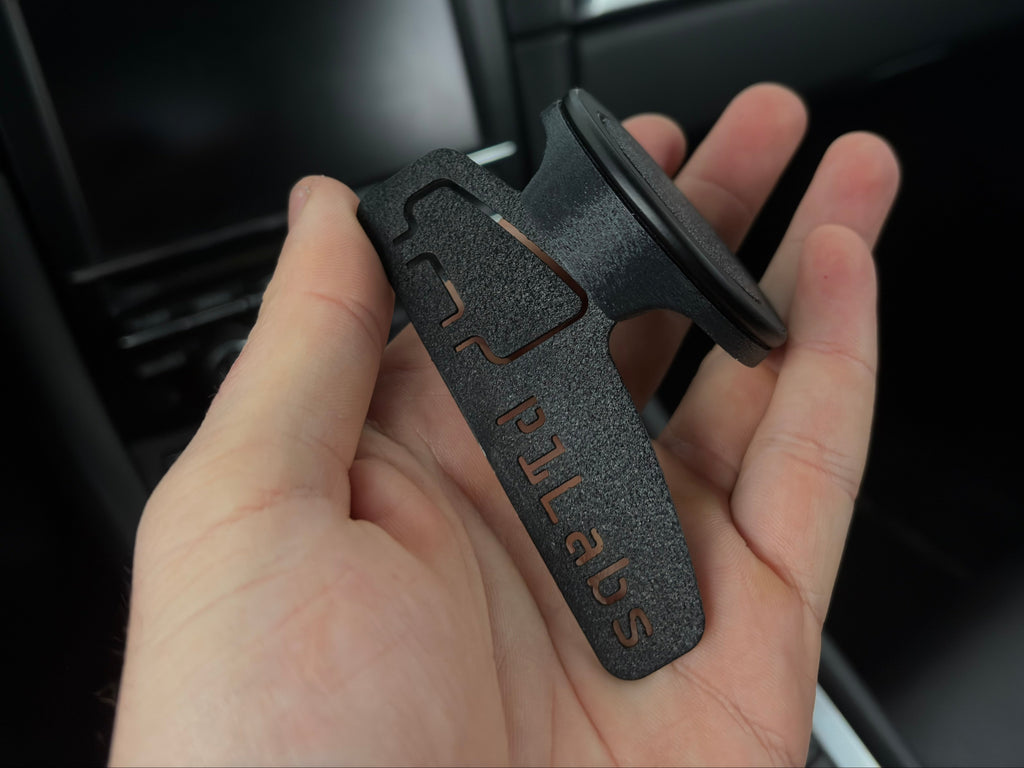 Hand holding a car mount with 'PULABS' branding against a car interior background