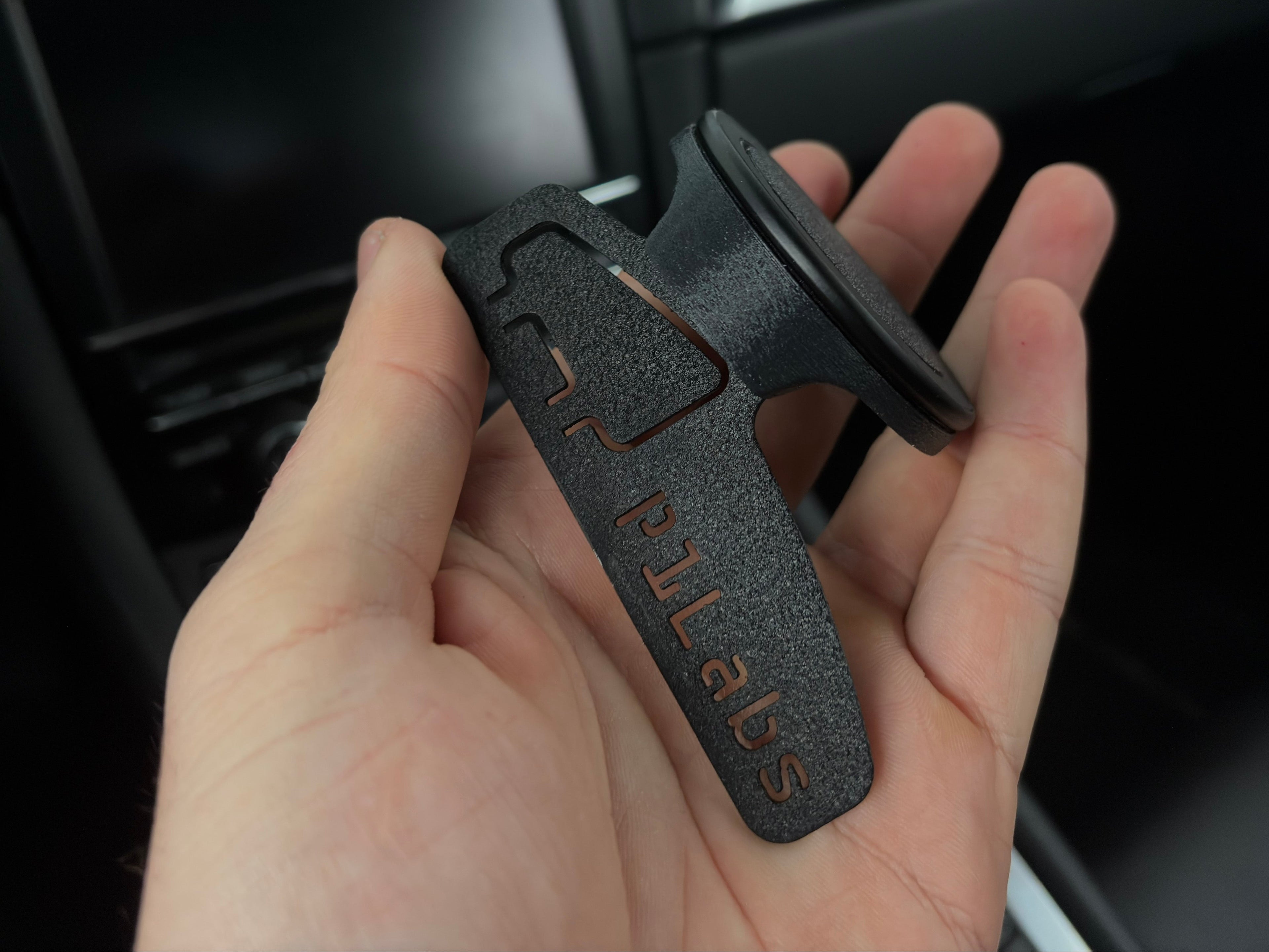 Hand holding a car mount with 'PULABS' branding against a car interior background