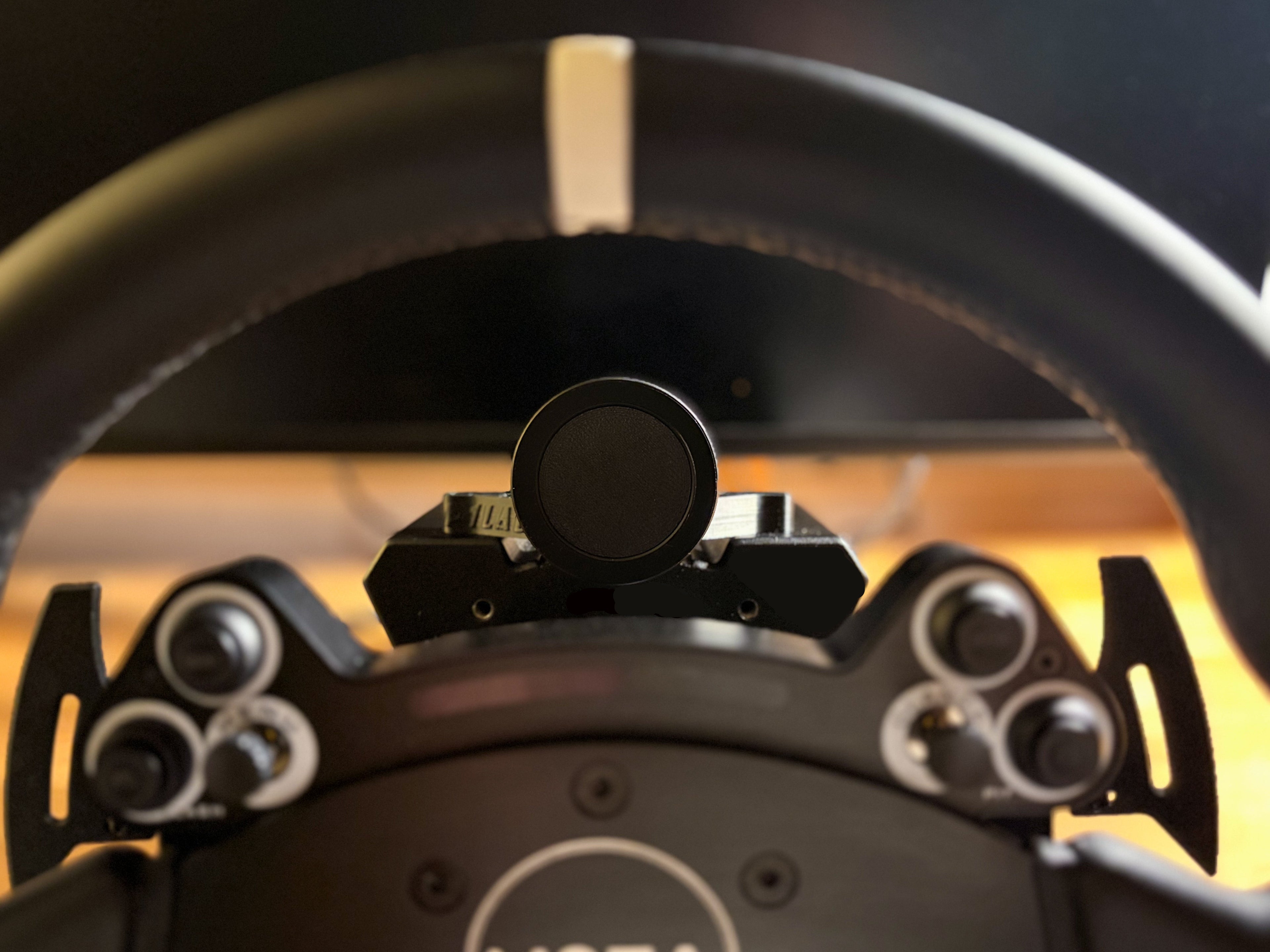 Round magnetic phone mount attached to a wheelbase. View from drivers perspective.