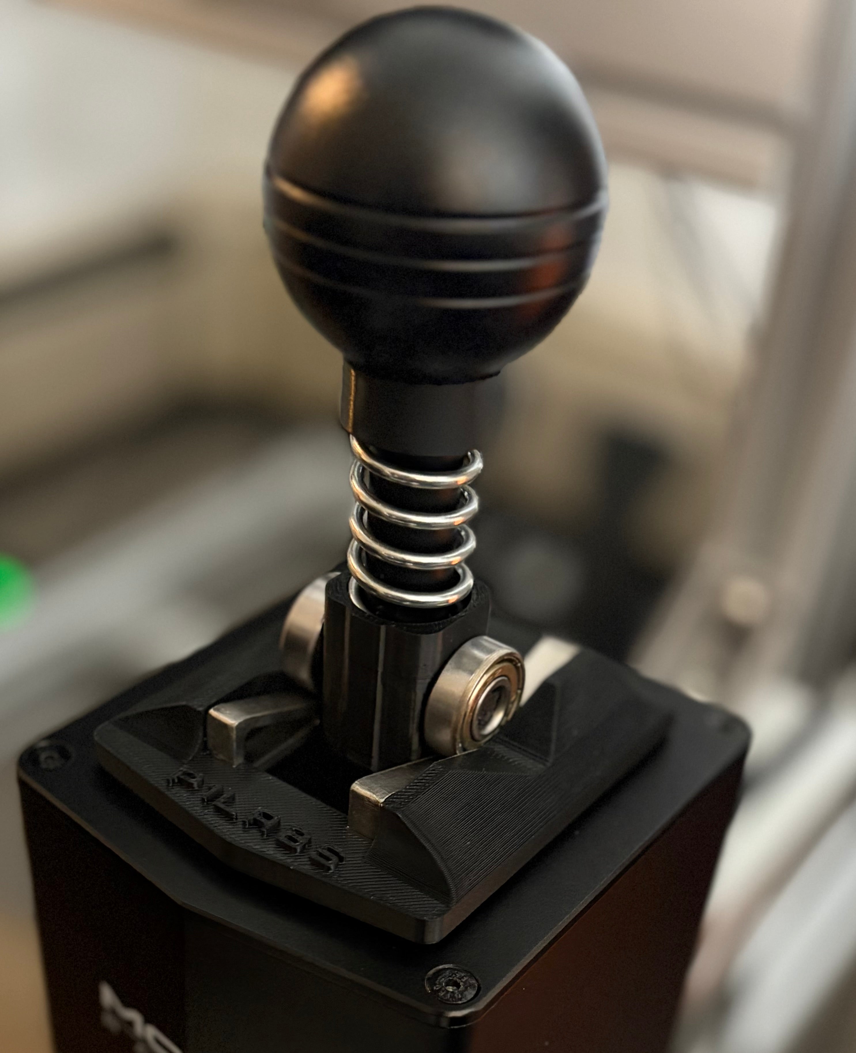 Close-up of a black gear shift lever with visible branding on a blurred background